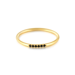 Detail shot of a slim golden ring featuring six small pavé-set black gemstones