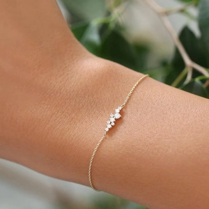 Macro shot of a minimalist 18k gold S925 silver bracelet with clustered white diamonds