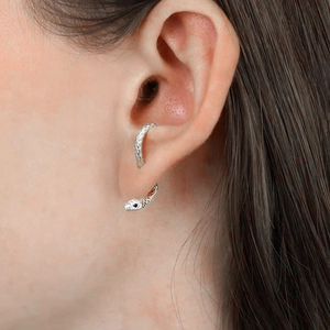 Macro view of silver snake-shaped ear cuff featuring scale texture and black gemstones