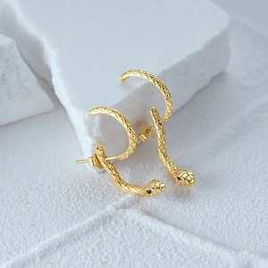 Detail of golden snake stud earrings with textured scales and black gemstone eyes