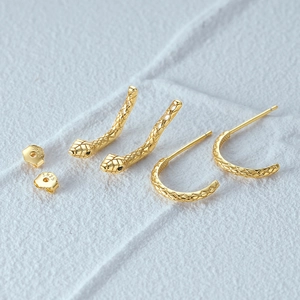 Detailed macro view of S925 sterling silver snake earrings with gold plating and scales