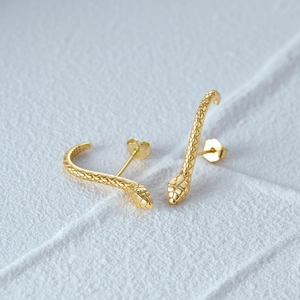Detailed view of gold snake earrings featuring intricate diamond scale textures and studs