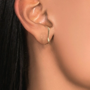 Close-up of golden snake earring with detailed scales on model ear in street style