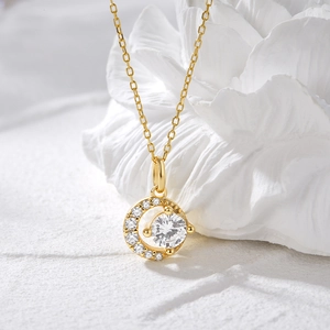 Vue macro du pendentif lune dorée avec un grand zircon central et des diamants pavés