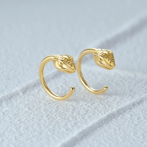Detailed macro shot of a gold-plated snake head stud earring with intricate scale textures