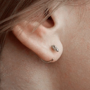 Gothic silver crow skull earring featuring a unique wrap-around behind-the-ear design