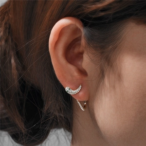 Detail of silver snake ear studs featuring white micro-pave crystals and green gemstone
