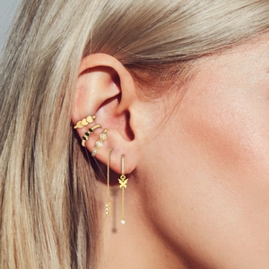 Détail de manchettes d'oreilles dorées avec zircons noirs et breloque papillon