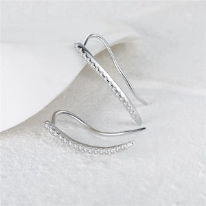 Close-up of S925 silver ear crawler earrings with sparkling zircon stones on white stone
