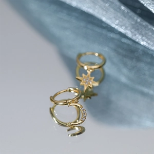 Macro shot of asymmetrical gold S925 silver star and moon earrings with sparkling zircon