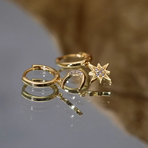 Macro detail of gold-plated S925 silver earrings with asymmetric star and moon charms