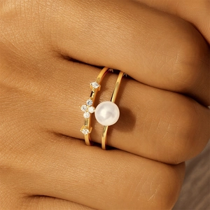 Detail of vintage gold stackable rings featuring a white pearl and sparkling zircon stars