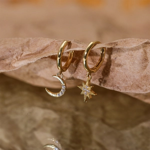 Macro shot of asymmetric gold star and moon earrings with micro-inlaid zircons