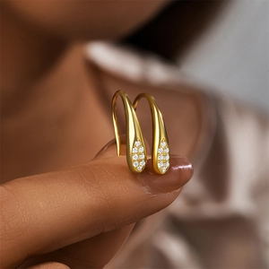 Close-up of elegant gold water drop earrings with micro-set zircon on the fingertips