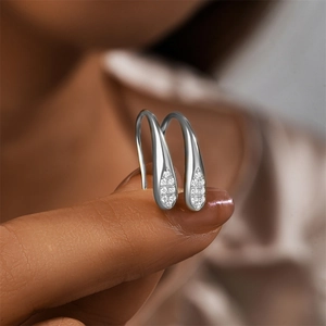 Detailed view of teardrop silver earrings with micro-pave crystals held for scale