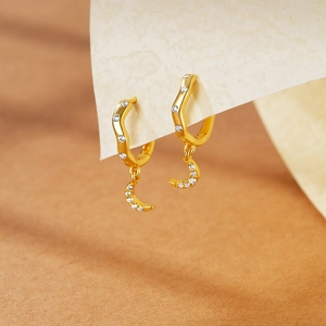 Detail of gold crescent moon earrings with cubic zirconia inlay on textured background