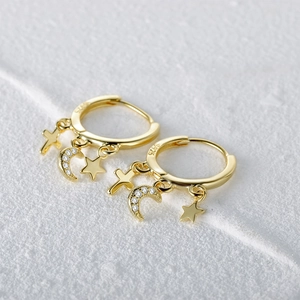 Macro shot of S925 sterling silver gold earrings with moon, star and cross charms