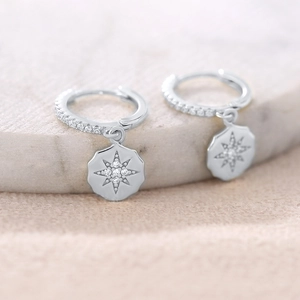 Macro shot of S925 silver huggie earrings with sparkling North Star pendant detail