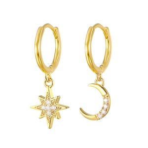 Macro detail of asymmetric gold S925 silver earrings with sparkling moon and star charms
