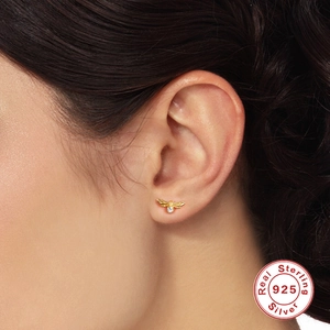 Minimalist 925 sterling silver bee stud earring with zircon on a person's ear lobe