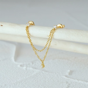 Detail van gouden multi-ketting oorbellen met fonkelende zirkoon op een takje