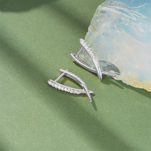 Detail of S925 sterling silver V-shape earrings with zircon inlay on green texture background