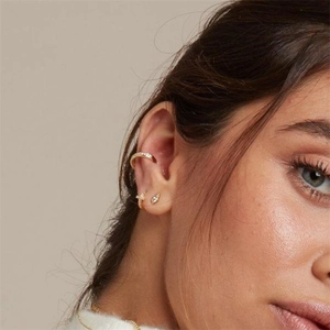 Close-up of elegant gold plated earrings set with sparkling stones on a model's ear