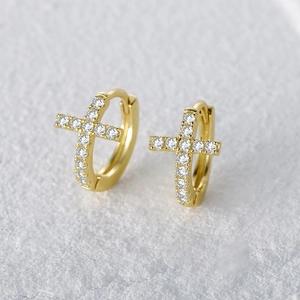 Macro view of gold s925 silver cross huggie earrings with sparkling white zircons