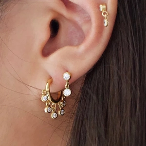 Close-up of gold-plated cluster zircon tassel earrings and minimalist ear studs on ear