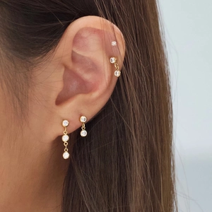 Detail view of gold S925 sterling silver ear studs set with clear cubic zirconia stones