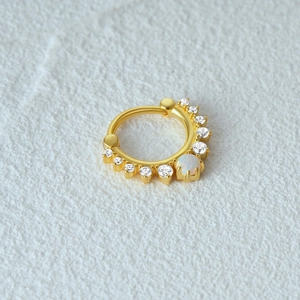 Macro shot of gold S925 silver ring with white zircon stones and iridescent opal center