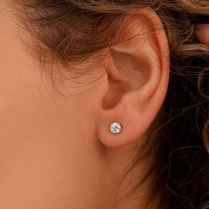Gros plan d'une boucle d'oreille en diamant rond portée sur le lobe de l'oreille