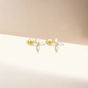 Gros plan détaillé des boucles d'oreilles fleur dorées à quatre pétales en cristal