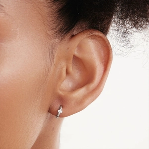 Close-up of minimalist S925 sterling silver hoop earring with a sparkling clover charm