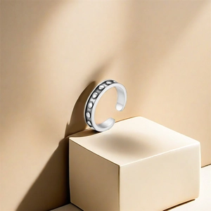 Artistic shot of embossed silver toe ring on beige geometric cubes for beach fashion