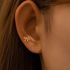 Gros plan d'un clou d'oreille nœud doré avec zircon blanc sur piercing tragus