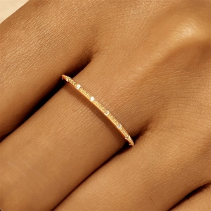 Detailansicht eines schmalen Goldrings mit Milgrain-Kante und Diamanten am Finger