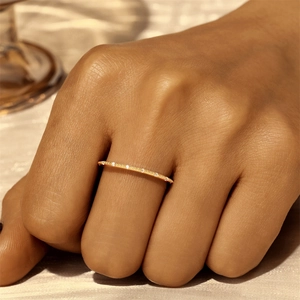 Nahaufnahme eines minimalistischen dünnen Goldrings mit Steinen an der Hand