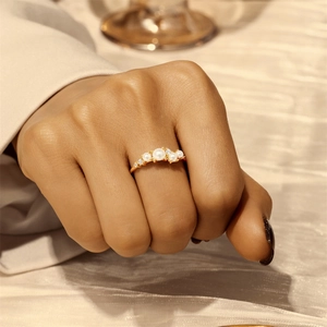 Nahaufnahme eines eleganten Goldrings mit fünf weißen Perlen und kleinen Diamanten