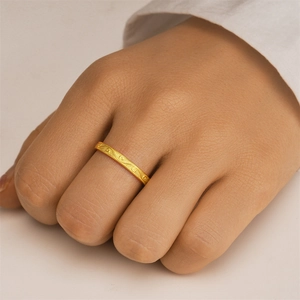 Detail eines eleganten Goldrings mit Vintage-Gravur und Perlenrand am Finger getragen