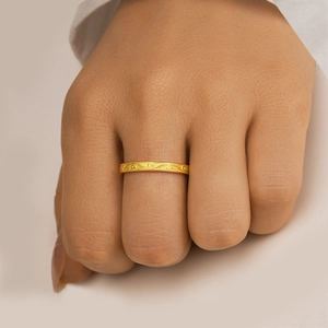 Detail eines schmalen Goldrings mit feiner Vintage-Gravur am Finger eines Models