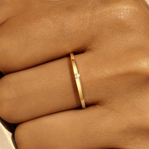 Detailansicht eines eleganten Goldrings mit funkelndem Diamanten an einem Finger