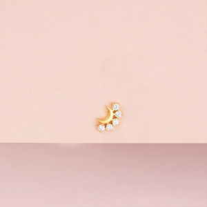 Détail d'un clou d'oreille croissant de lune doré avec cinq zircons blancs étincelants