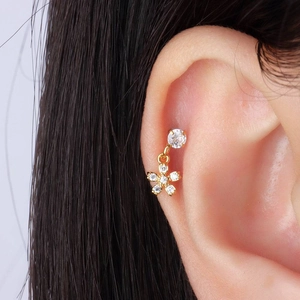 Vue rapprochée d'une boucle d'oreille fleur en or et zircons portee par un modèle
