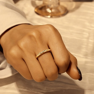 Nahaufnahme eines eleganten Doppel-Goldrings mit funkelnden weißen Diamanten an der Hand