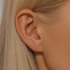 Détail macro d'un piercing tragus en argent 925 avec quatre diamants et fini doré