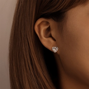 Gros plan sur boucle d'oreille cœur en argent S925 avec motif arbre de vie rose sur oreille