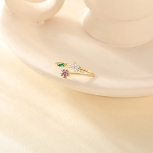 Detail of adjustable gold ring featuring purple floral gems and green marquise leaf