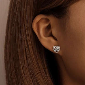 Gros plan sur des puces d'oreilles cœur en argent s925 avec détails émail papillon