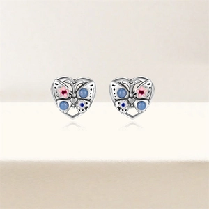 Détail de boucles d'oreilles cœur en argent S925 avec motifs papillon en émail